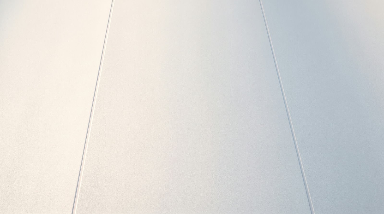 A flat run of matte white hygienic wall cladding, its welded joints dressed flush.